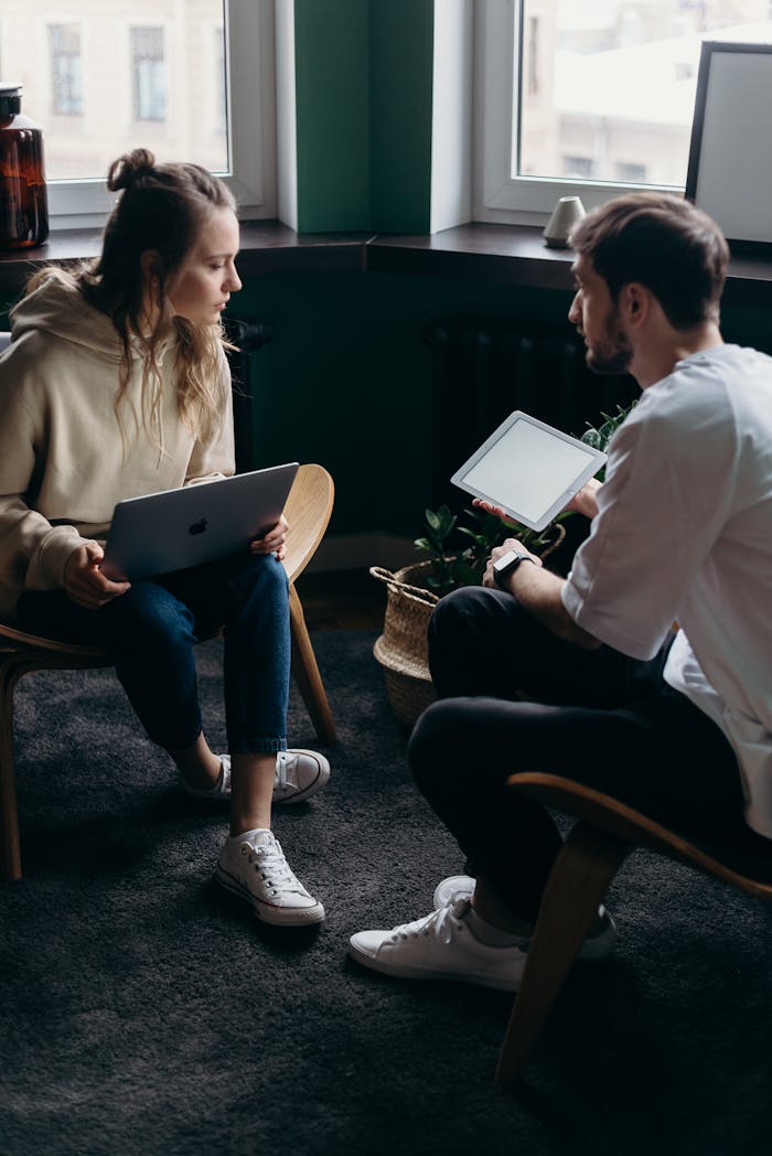 contact-header Two adults having a tech-focused discussion in a cozy home setting.